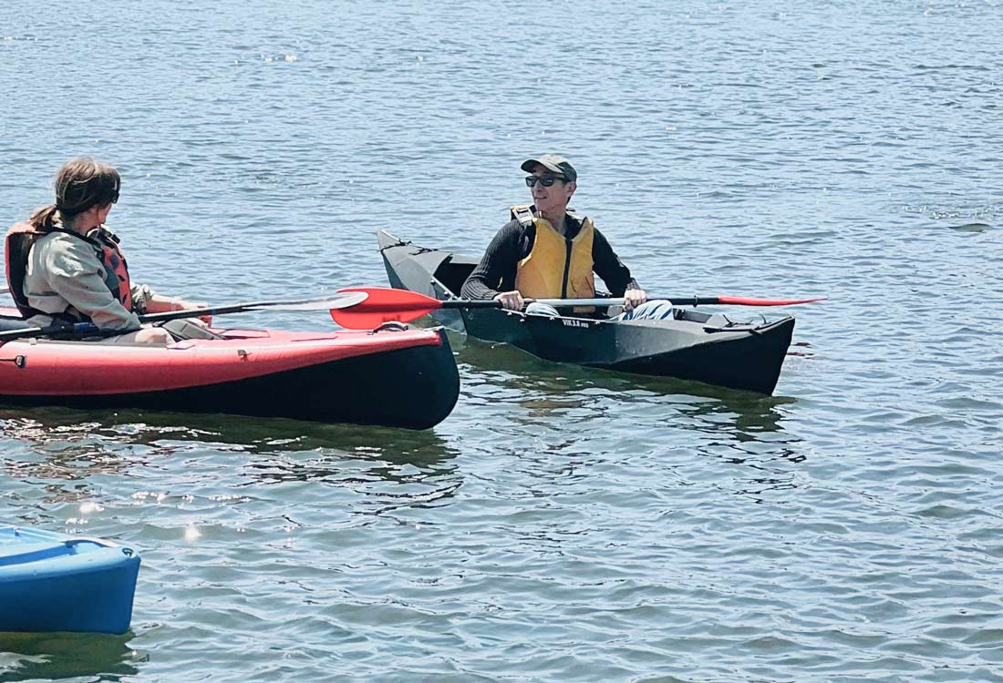 Vergleich zwischen einem Faltkajak mit festem Rahmen und einem aufblasbaren Schlauchkajak im Wasser.