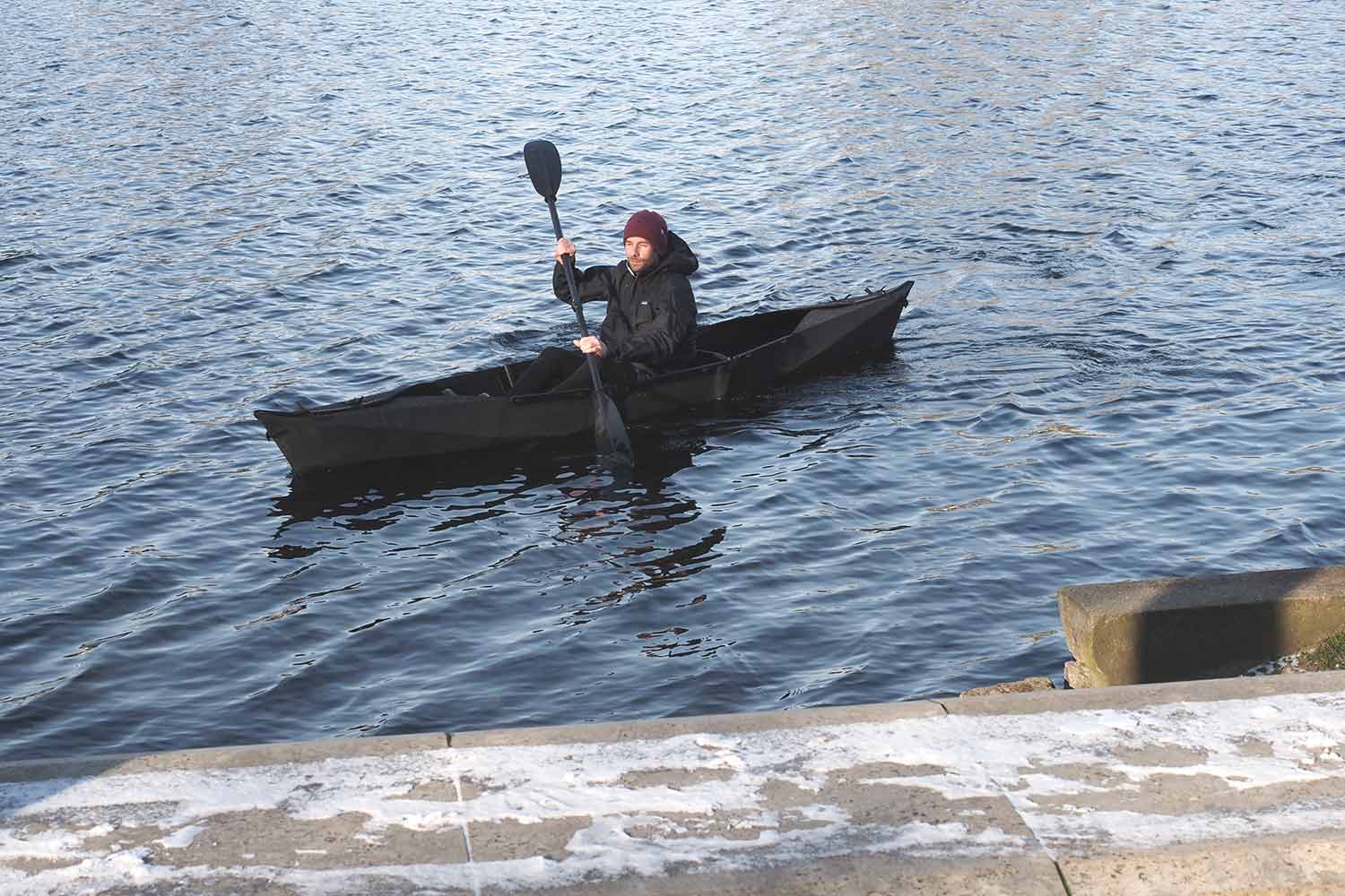 Ein schwarzes VIK Faltboot gleitet durch durch das Wasser im Winter.
