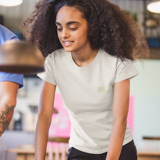 „Modell trägt das sand NEW WAVE Era T-Shirt von CLR Outdoor GmbH mit dezentem Logo-Print links auf der Brust, sommerlicher Streetwear-Style.“