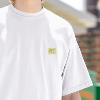 „Detailaufnahme des NEW WAVE Era T-Shirts von CLR Outdoor GmbH: dezenter rechteckiger Logo-Print in Gelb-Grün auf der linken Brust eines weißen Shirts.“