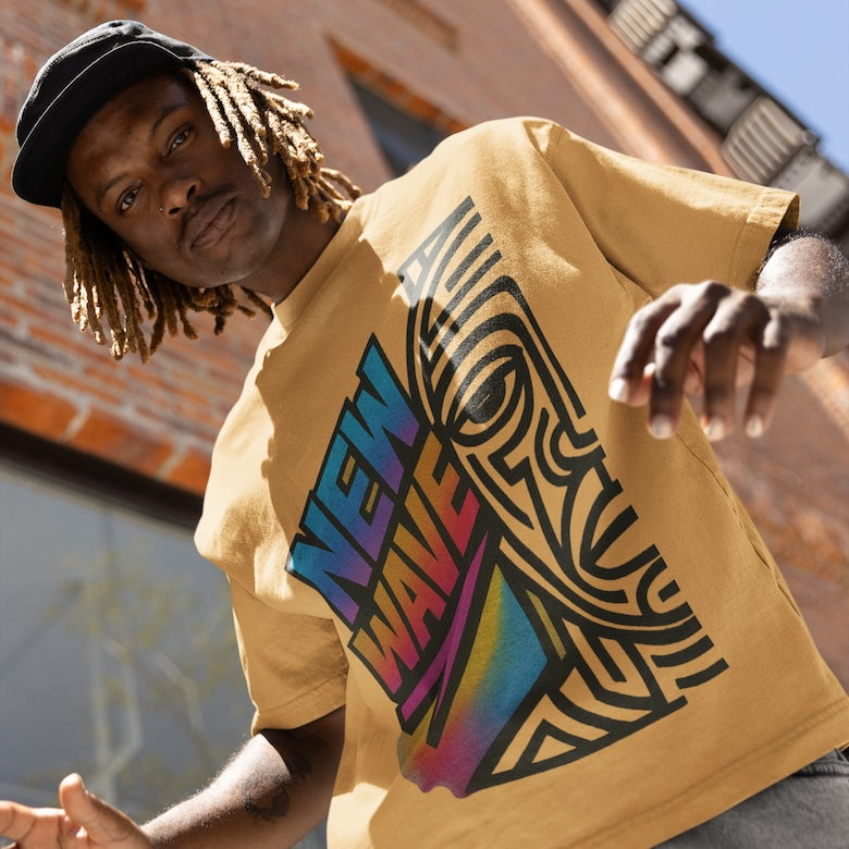 „Streetwear-Style: NEW WAVE Urban Society T-Shirt in Senfgelb von CLR Outdoor GmbH, bunter Print im Urban-Art-Stil, getragen vor roter Backsteinwand.“